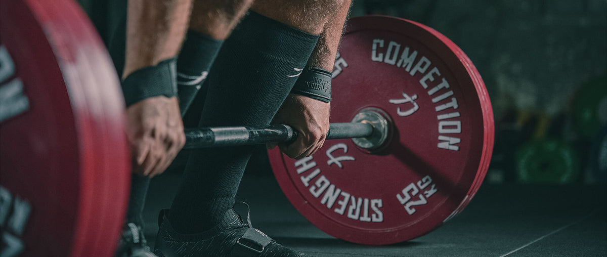 Lifter setting up a deadlift in Strength Shop wrist wraps and knee sleeves